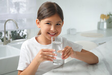 Girl Drinking Tap Water From Glass In Kitchen