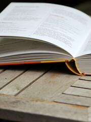 Poster - Closeup of an open hardcover book on the wooden surface