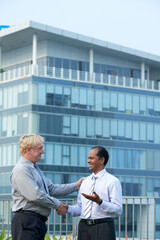 Wall Mural - Positive business partners shaking hands after having meeting outdoors in front of office building