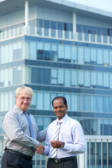 Wall Mural - Diverse business partners standing on balcony of office building and shaking hands to confirm deal