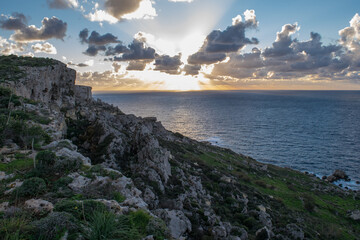 Poster - A peaceful cloudy sunset, as seen from on top of a sloping cliff along the coast of Mellieha, Malta.