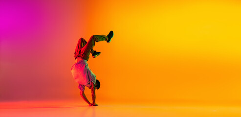 Wall Mural - Flyer with young stylish man, break dancing dancer training in casual clothes isolated over gradient pink yellow background at dance hall in neon light.