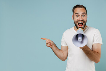 Poster - Young happy man in white t-shirt hold scream in megaphone announces discounts sale Hurry up point index finger aside on workspace area isolated on plain pastel light blue background studio portrait