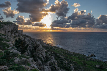 Poster - A peaceful cloudy sunset, as seen from on top of a sloping cliff along the coast of Mellieha, Malta.