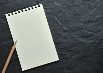 Wall Mural - top table view, open blank spiral notebook on black background, copy space for text.