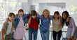 Group of happy diverse teen schoolchildren hugging and smiling at camera
