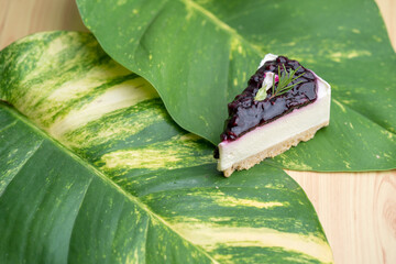 Sticker - Slice of blueberry cheesecake on green leaves at the table