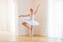 Young Slender Ballerina In A White Tutu In Pointe Shoes Is Dancing In Large Beautiful White Hall.