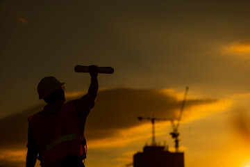 Poster - silhouette of engineer and construction site background at sunset