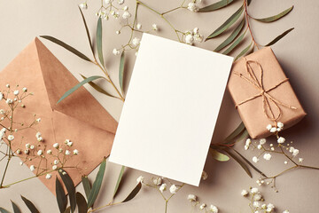 Greeting card mockup with gift box and envelope decorated with eucalyptus and gypsophila twigs. Card mockup with copy space.