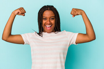 Young african american woman isolated on blue background  showing strength gesture with arms, symbol of feminine power