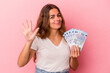 © Asier - Young caucasian woman holding bills isolated on pink background  smiling cheerful showing number five with fingers.