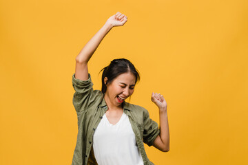 Young Asia lady with positive expression, joyful and exciting, dressed in casual cloth over yellow background with empty space. Happy adorable glad woman rejoices success. Facial expression concept.