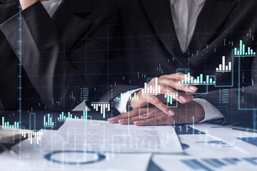 Wall Mural - Two traders researching historic data to predict stock market behavior. Women in trading business concept. Forex and financial hologram chart over the table with the document.