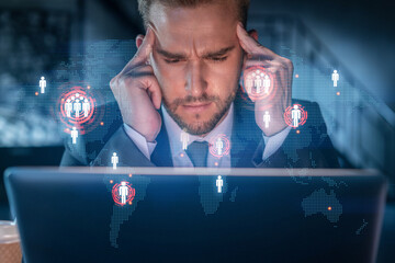 Wall Mural - Handsome businessman in suit at workplace working with laptop to hire new employees for international business consulting. HR, social media hologram icons over office background