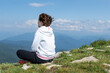 © Anna - Close up image of young female in sport clothers seat on peak of green summer mountains, copy space. relaxation in beautiful nature.