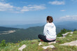 © Anna - Young female in sport clothers seat on peak of green summer mountains, copy space. relaxation in beautiful nature.