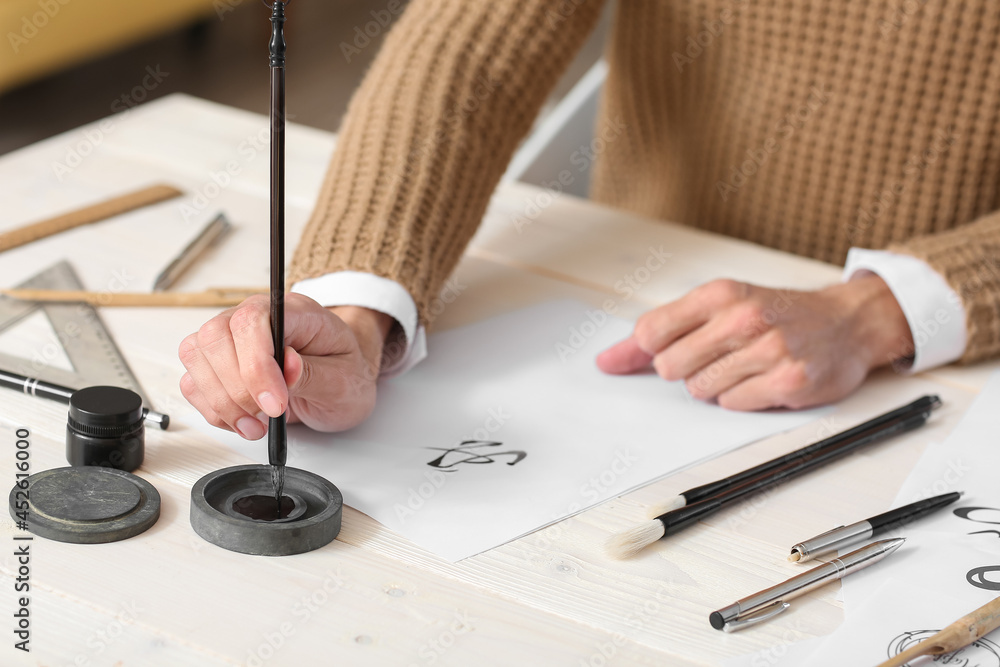 Young male calligrapher working in office, closeup