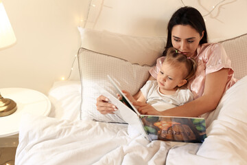 Poster - Mother and little baby reading book in bed