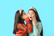 Cute Little Girls Telling Secrets To Each Other On Color Background