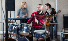 Rehearsal Of A Music Group. Rock Band With Emotional Male Drummer Playing In Recording Studio