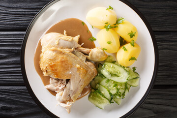 Canvas Print - Danish fried old-fashioned chicken with boiled potatoes and cucumber salad close-up in a plate on the table. horizontal top view from above