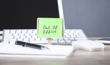 Out of office message on sticky note with computer.