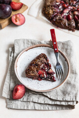 Wall Mural - Homemade galette or open pie with chocolate, plum and almond on light concrete background.