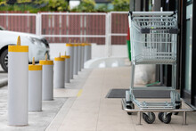 Blank Shopping Cart In Front Of Convenience Store On Walk Way Path With Steel Bollards Near Parking Lot.