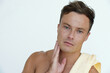 © DragonImages - Portrait of shirtless attractive serious young man touching soft skin of his face after morning shower