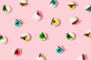 Wall Mural - Creative pattern made with eyeball figurines with eyelashes on pastel pink background. Halloween minimal creative concept. Rainbow colored eyes. Modern fashion aesthetic or cosmetic idea.