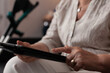 © DC Studio - Close up of old woman hand using tablet screen display browsing online internet website sitting at home while having crutches on couch. Retired caucasian person learning technology
