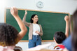 © eggeeggjiew - Asian teacher and Diverse Multi ethnic Little Student raising their hands in classroom