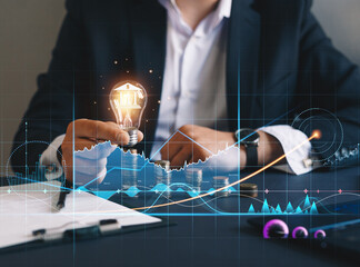 Financial technology with growth chart that helps to develop services and profits in global business. Businessman holding light bulb with banking icon.