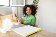© PintoArt - child does homework at home, rests to drink a refreshing drink, while looking at his cat