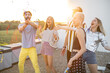 Young stylish friends have fun, shooting confetti during some celebration at rooftop terrace on a sunset
