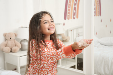 Canvas Print - Cute little girl in pajamas playing with feathers at home. Happy childhood