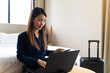 © structuresxx - Asian businesswoman using laptop working in hotel room remotely on her business travel