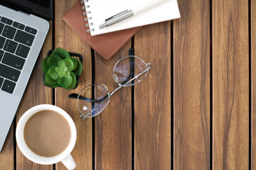 Wall Mural - Desk office with laptop computer and coffee cup, blank notepad and pen on brown wood table background with copy space, Flat lay