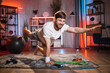 © sofiko14 - Handsome active strong young bearded man in sportswear, doing opposite arm and leg raise exercises on the floor carpet during evening home workout