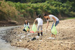 © sutlafk - Group of volunteer people collecting trash near river. Ecology charity and clean environment concept
