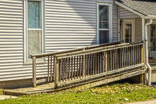Rustic Wooden Handicap Ramp On Vintage House With Fabric Tacked Up Inside Windows And Metal Drainpipe On Porch - College Town.