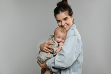 beautiful mother with her cute baby on grey background. space for text
