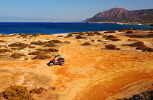 Aerial View Of Buggy Car On The Sandy On The Sea Coast Of Cyprus Or Greek In Summer. Extreme Trip Off Road Place. Outdoor Adventure For Tourists