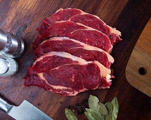 Wall Mural - Piece of beef with peas of bitter pepper and laurel leafs on dark broun cutting board