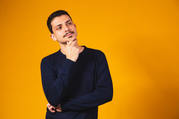 Young thoughtful student boy on yellow background. young man thinking and having an idea