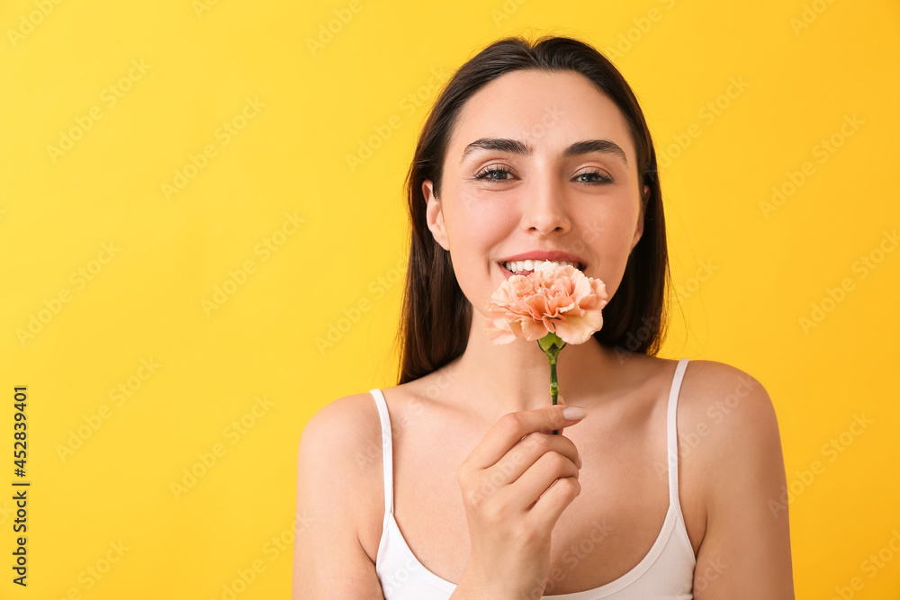 Young woman with beautiful carnation flower on color background