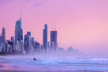 Sunlit Skies Over Surfers Paradise Cityscape, With Surfer Going Into The Ocean