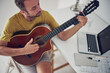 © astrosystem - Man playing acoustic guitar at home.