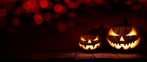Wall Mural - three scary halloween lanterns with evil eyes and faces on a rustic wood table with a spooky dark re